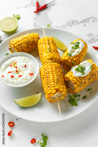 Grilled sweet corn with white mexican sauce, chilli and lime. healthy summer food