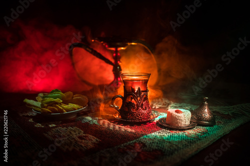 Hookah hot coals on shisha bowl making clouds of steam at Arabian interior. Oriental ornament on the carpet eastern tea ceremony. Stylish oriental shisha in dark with backlight.