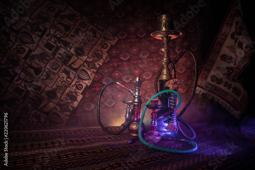 Hookah hot coals on shisha bowl making clouds of steam at Arabian interior. Oriental ornament on the carpet. Stylish oriental shisha in dark with backlight. For Shisha advertisement. photo