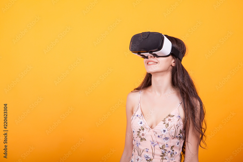 Girl wearing a VR headset and experiencing virtual reality, technology and innovation concept in studio over yellow background.Much gesticulating hands Girl wearing a VR headset and experiencing virtual reality, technology and innovation concept in studio over yellow background.Much gesticulating hands