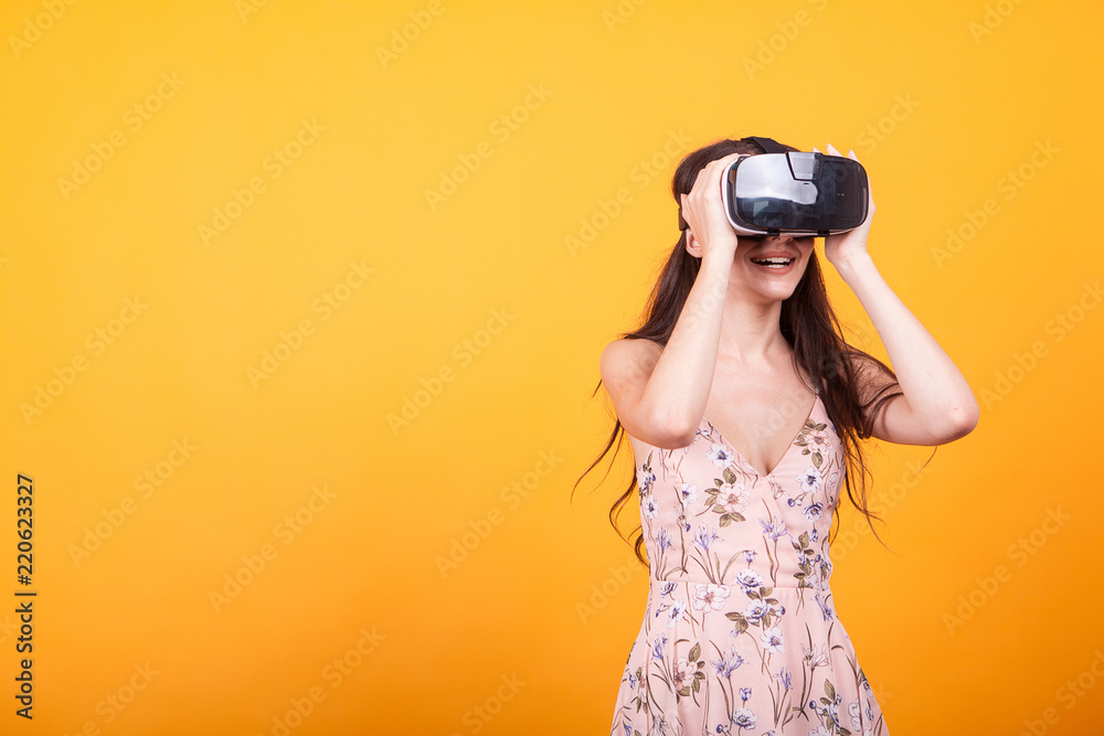 Girl plays vr game in virtual reality helmet in studio over yellow background. Studio portrait of girl playing mobile app on VR Glasses. Girl plays vr game in virtual reality helmet in studio over yellow background. Studio portrait of girl playing mobile app on VR Glasses.