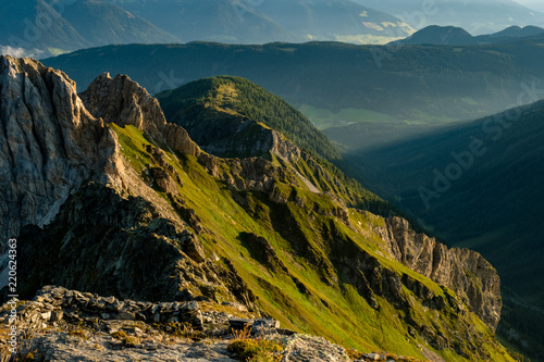 Grüne Almwiese wird von den ersten Sonnenstrahlen in den österreichischen Bergen erhellt