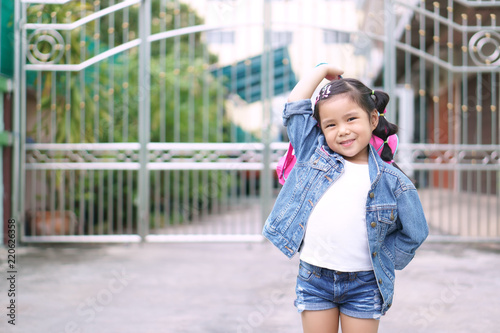 Asian children or kid girl smile and student holding and show pink schoolbag with happy fun because go to school or back to school and kindergarten from summer study or learning to home and wear jeans