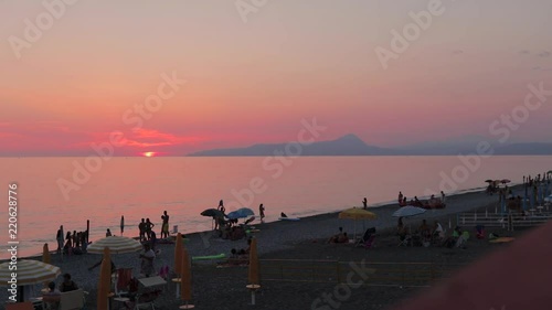Bellissimo tramonto sul mare italiano. Mare turchese illuminato dal sole arancione.  Silhouette montagna in background