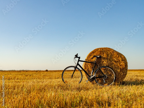 Bicycle in the field with big round bales of straw