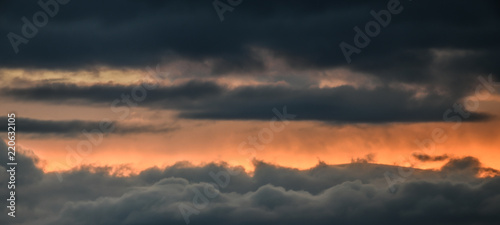 Panoramic - Flying high above dark clouds at sunset.  Front view of passage through dramatic clouds. High def image. Concept for fear of flying  fly high  hope  silver lining  break in the clouds