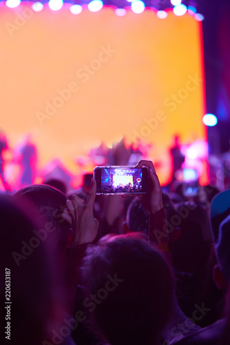 Use advanced mobile recording, fun concerts and beautiful lighting, Candid image of crowd at rock concert, Close up of recording video with smartphone, Enjoy the use of mobile photography.