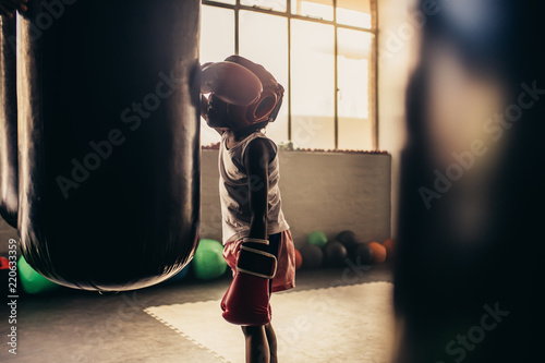 Boxing kid standing in front of a punching bag at a boxing gym