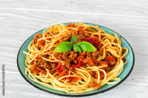 Spaghetti bolognese on a blue plate on white wooden table. healthy food. close up