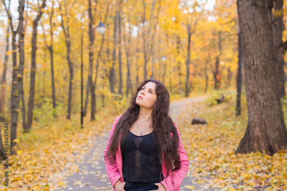 Autumn, nature and people concept - young woman watching the sky in autumn park. She is in pink jacket Autumn, nature and people concept - young woman watching the sky in autumn park. She is in pink jacket