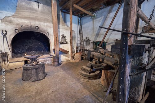 Interior of the old mediaeval vintage water powered blacksmith workshop or forge with hammer, anvil, tools and furnace, old technology still working in Czech Republic.