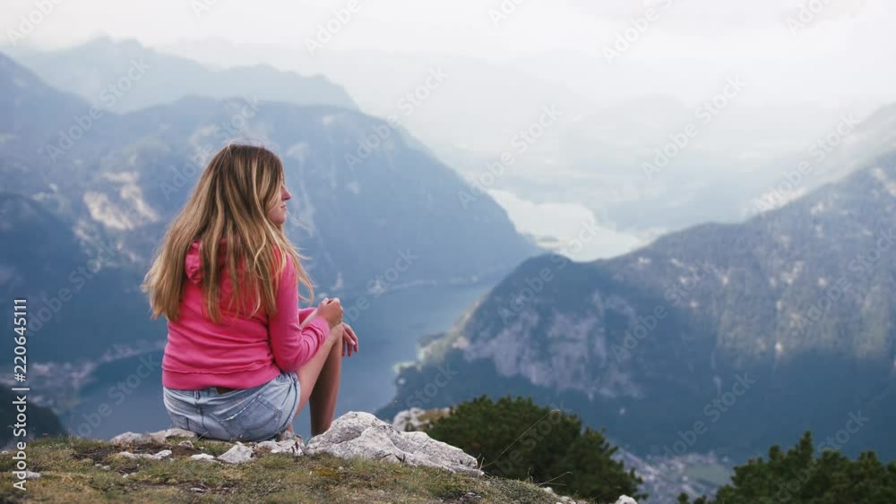Woman sitting on mountain top and contemplating beautiful view Woman sitting on mountain top and contemplating beautiful view