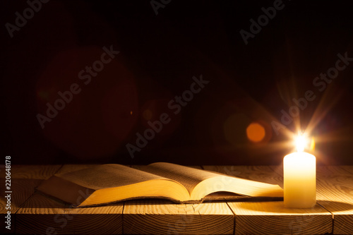 Fotografiet a bible on the table in the light of a candle