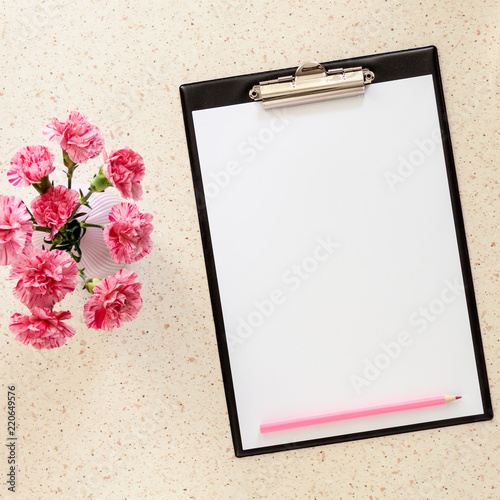 Photo of terrazzo desk with mockup of office pad  pink carnations in a vase and pink pencil