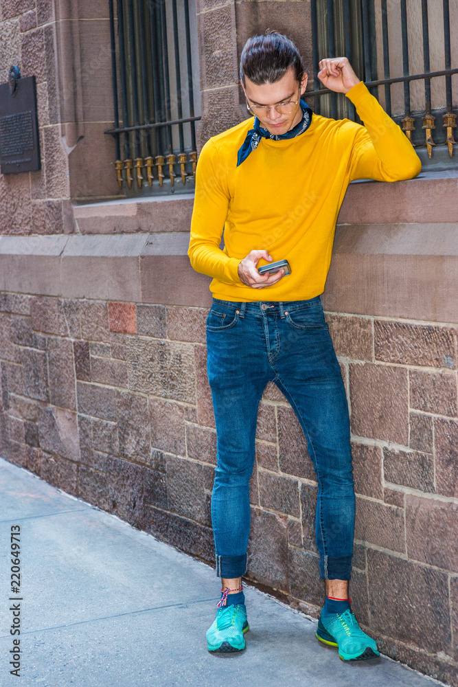 Young Hispanic American Man wearing glasses, yellow long sleeve T shirt,  jeans, green patterned sneakers, small