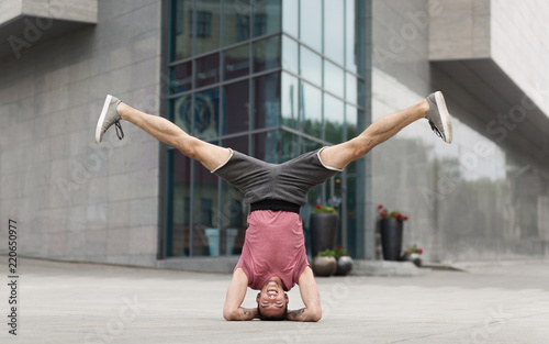 Young man doing yoga headstand exercise outdoors