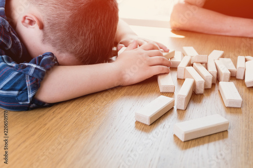 Kid lost the jenga game. His tower from wooden blocks had fallen. Concept of risk and strategy in business and construction. photo