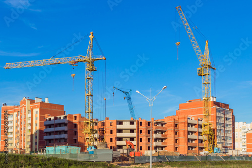 Construction of residential multi-storey houses with a cranes in the foreground