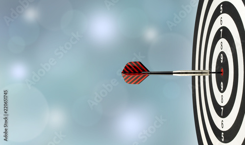 close-up dart arrow hitting on target center on bullseye in wooden dartboard with blurred blue lights bokeh copy space background, perfection goal success, symbol of aim and achievement