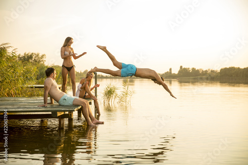 Group of young people having fun on pier at the lake
