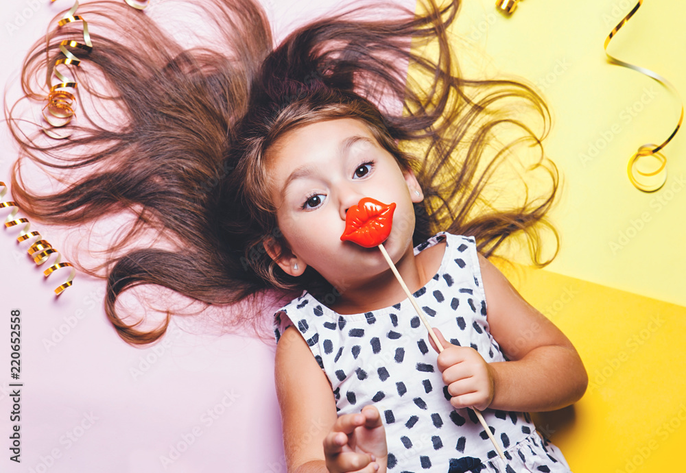 Cute little girl in funny glasses with plastic masquerade lips on stick. Cute little girl in funny glasses with plastic masquerade lips on stick.