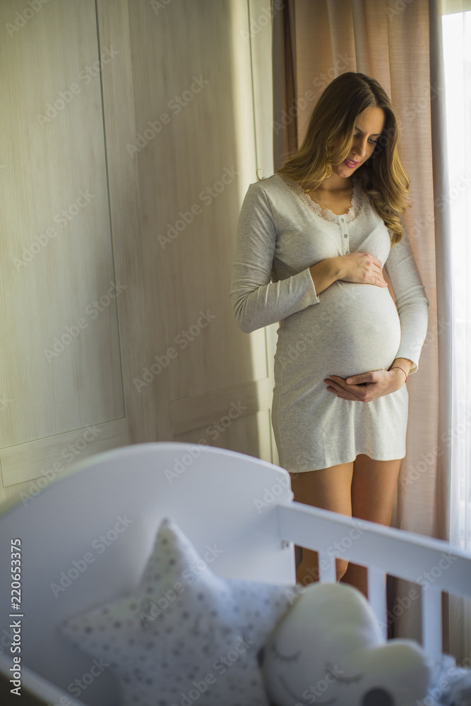 Young pregnant woman by the cradle in the room Young pregnant woman by the cradle in the room