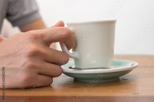 a cup of coffee with holding hand man on wooden table 