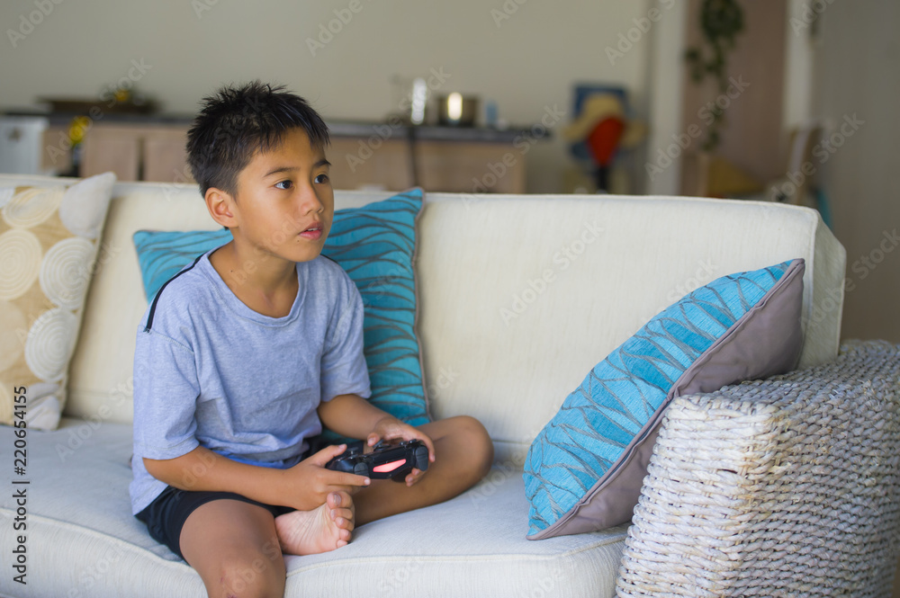 Latin young kid 8 years old excited and happy playing video game online  holding remote controller enjoying having fun on couch in child gaming  addiction Stock-foto | Adobe Stock