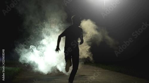 The fellow running in the cloud of smoke on the dark background, slow motion photo