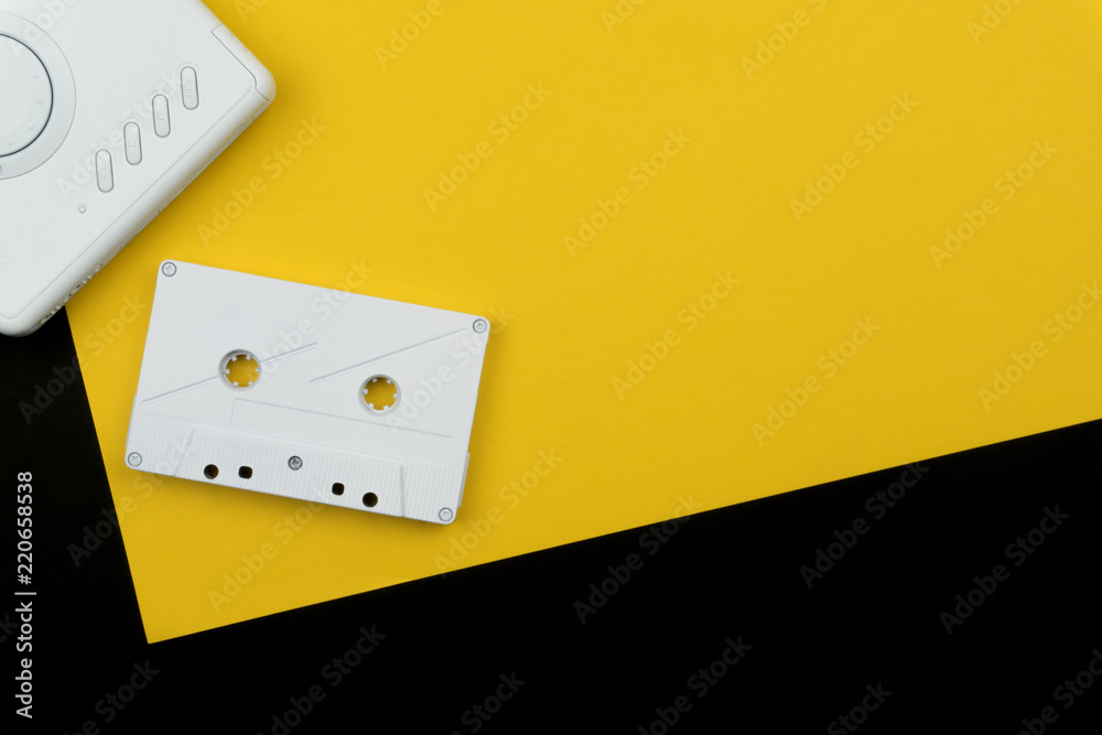 a white audio cassette tape with a white portable cassette player on the yellow and black background a white audio cassette tape with a white portable cassette player on the yellow and black background