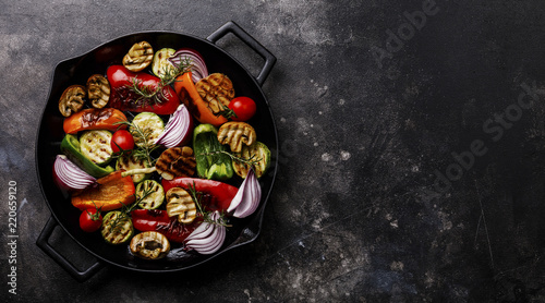 Grilled assorted vegetables in cast iron pan on dark background copy space photo