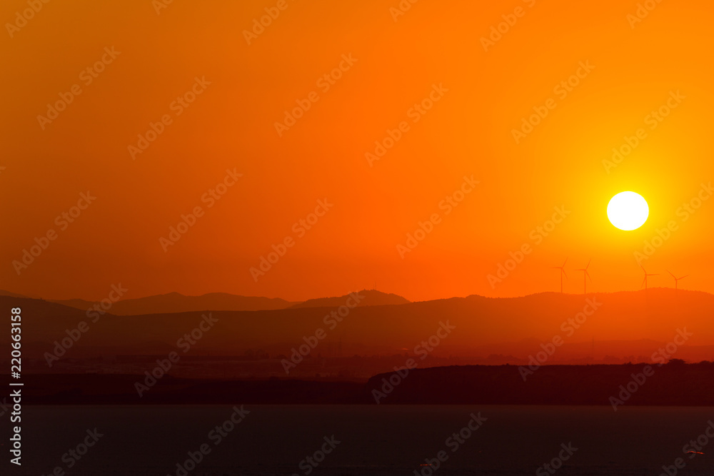 Overall view of wind power generators on the background of sunset over dry salt lake in Cyprus Larnaca in summer