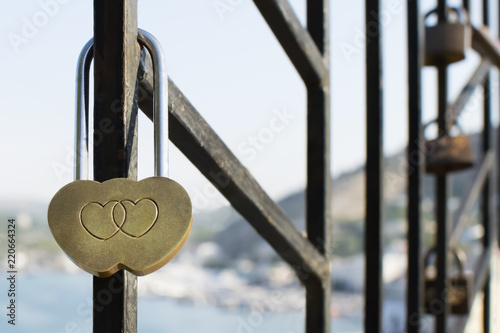 beautiful golden lock with engraving of two hearts that touch each other against the background of old rusty locks