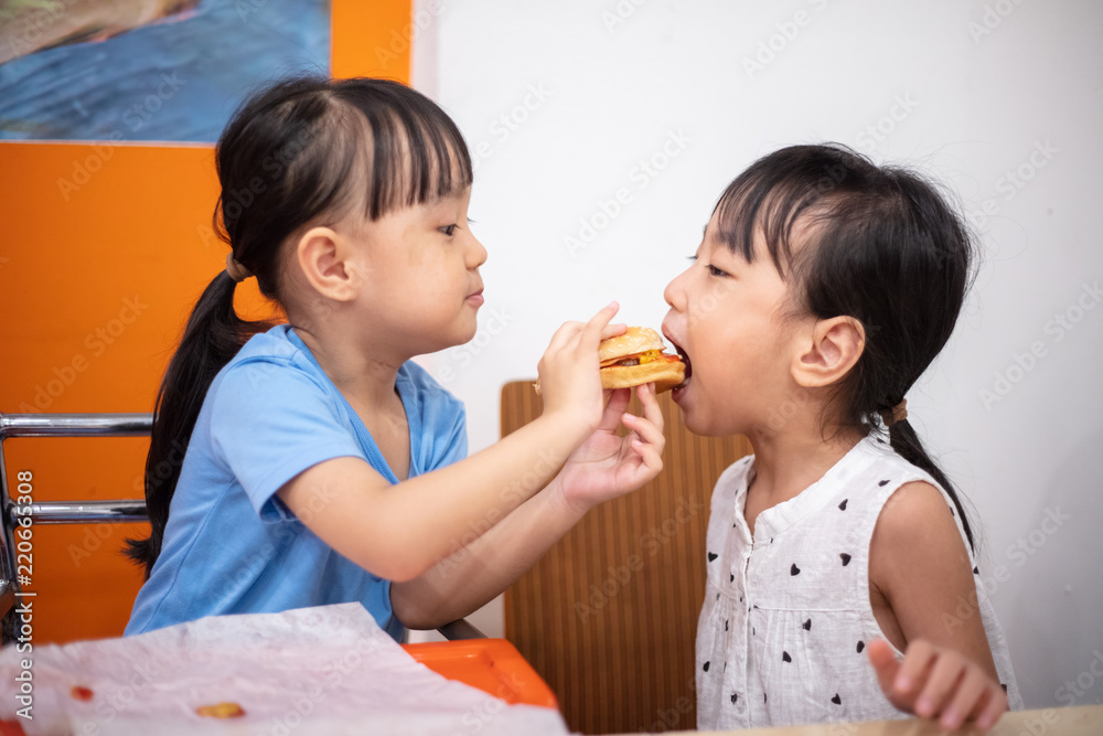 Asian Chinese little sisters eating burger Asian Chinese little sisters eating burger