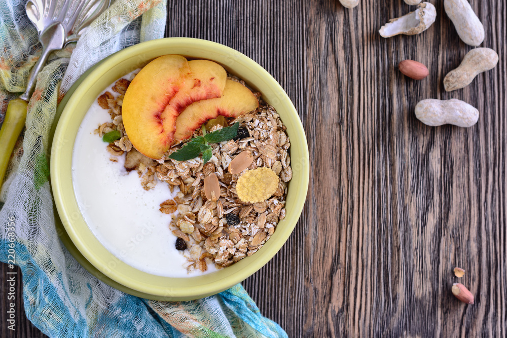 Useful breakfast of muesli with peach slices is in a bowl on a wooden table Useful breakfast of muesli with peach slices is in a bowl on a wooden table