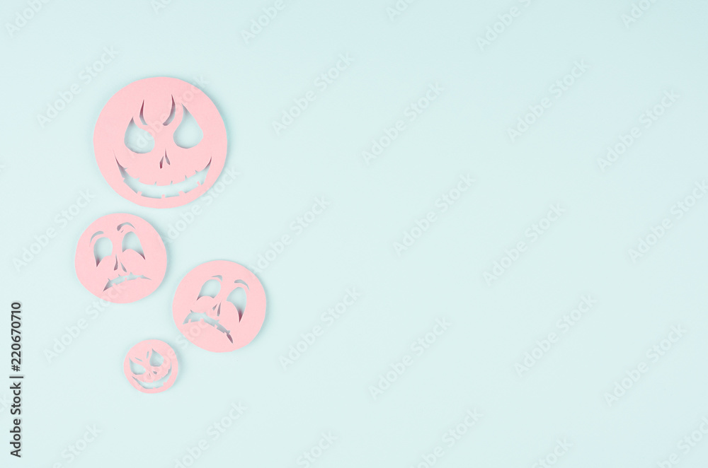 Halloween background - pink spooky faces emoji of cut paper on pastel trendy mint color.