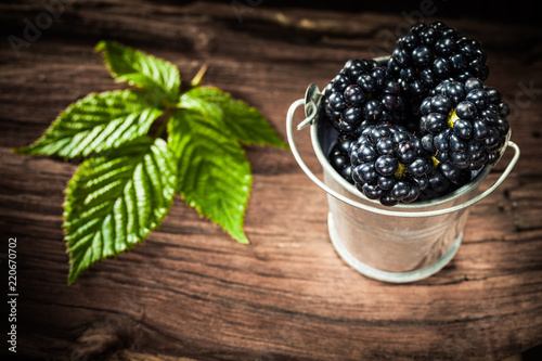 Sweet blackberries in bucket leaf on vintage wooden board