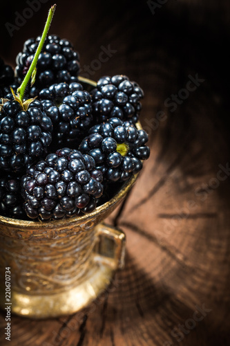 Sweet blackberries in metal bowl on vintage wooden board