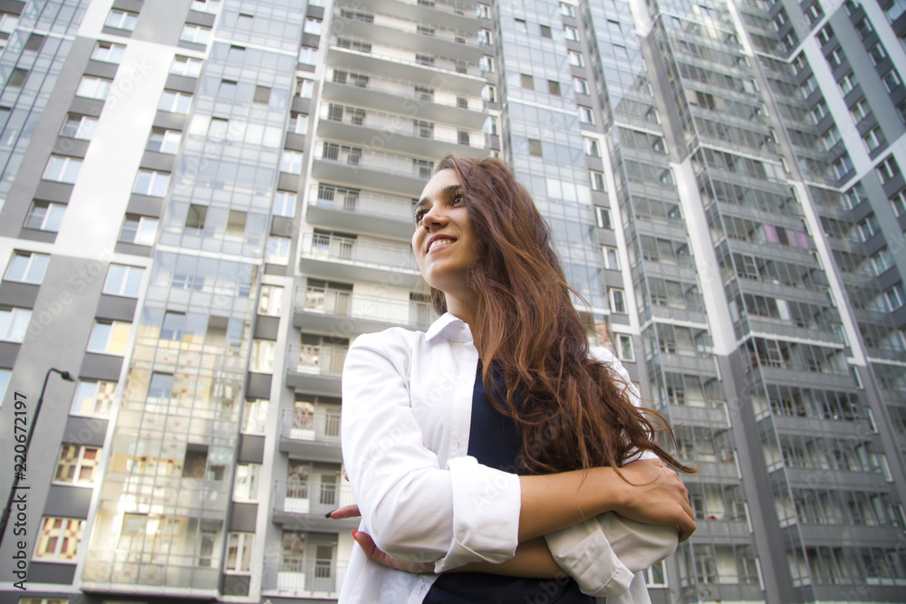 The girl is standing on the background of new buildings The girl is standing on the background of new buildings