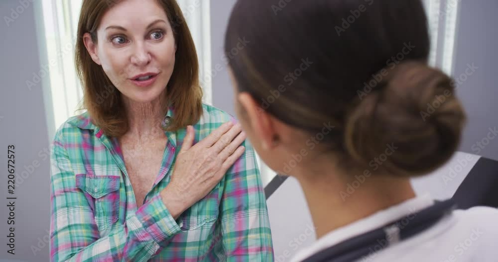Close up of charming mid aged patient explaining to doctor her shoulder pain Close up of charming mid aged patient explaining to doctor her shoulder pain