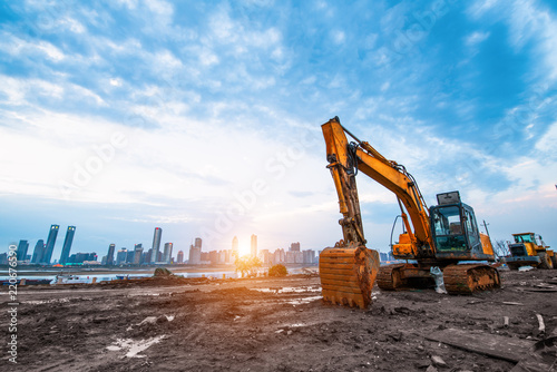 excavator in construction site on sunset sky background photo
