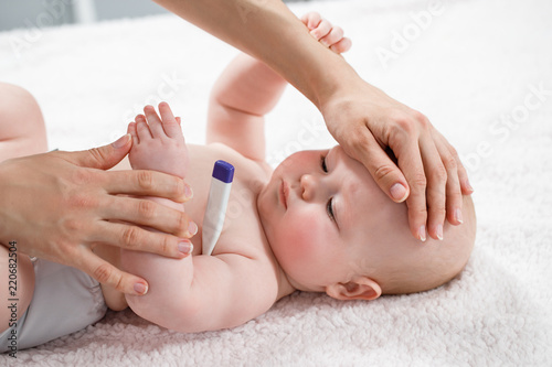 Woman measuring temperature of small sick boy