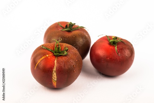Three dark tomato on white.