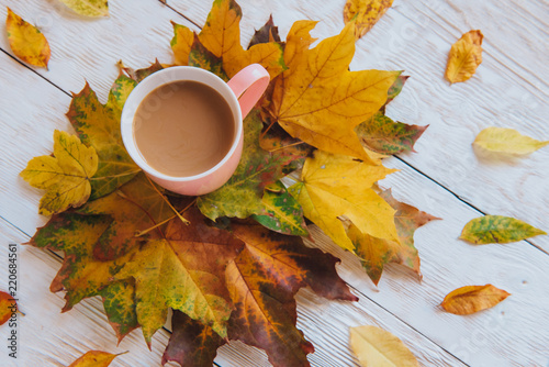 Coffee cup and yellow autumn leaves background. Still life, top of view, flat lay.