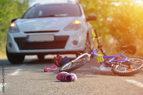 Close-up of a kid shoe fallen on the asphalt next to a bicycle after car accident on the street in the city
