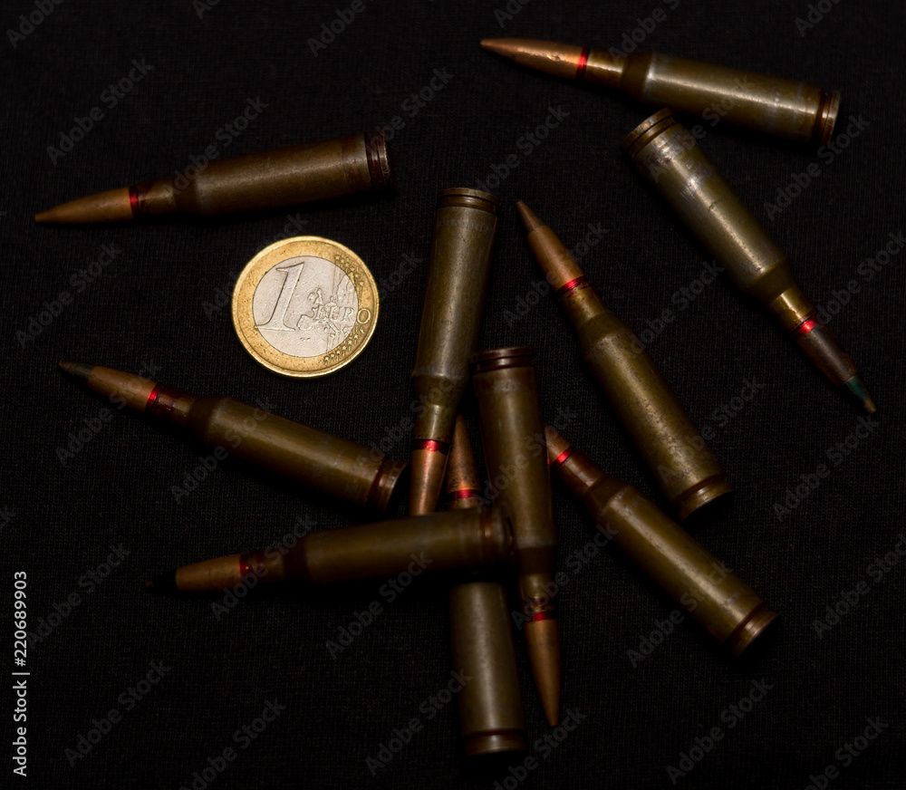 Rifle ammo around one euro coin on black background. Symbolizes the war for money and one of the world's problems. Rifle ammo around one euro coin on black background. Symbolizes the war for money and one of the world's problems.