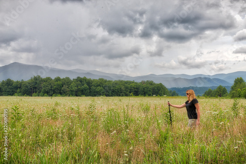 Caucasian woman walking in a green meadow in the Great Smoky Mountains on a cloudy day
