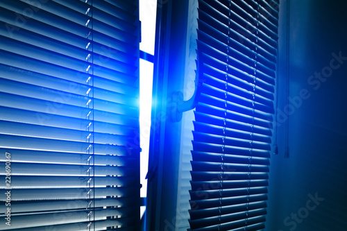 The background of the half-open window with blinds, sunlight through an open window