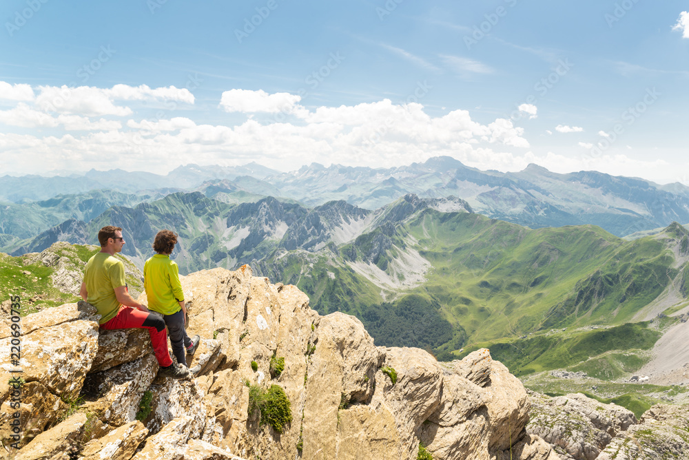 Pareja joven en la cima de una montaña mirando el impresionante paisaje. Concepto de vacaciones de aventura activa.