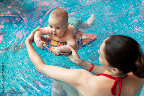 baby with mom learns to swim in the pool